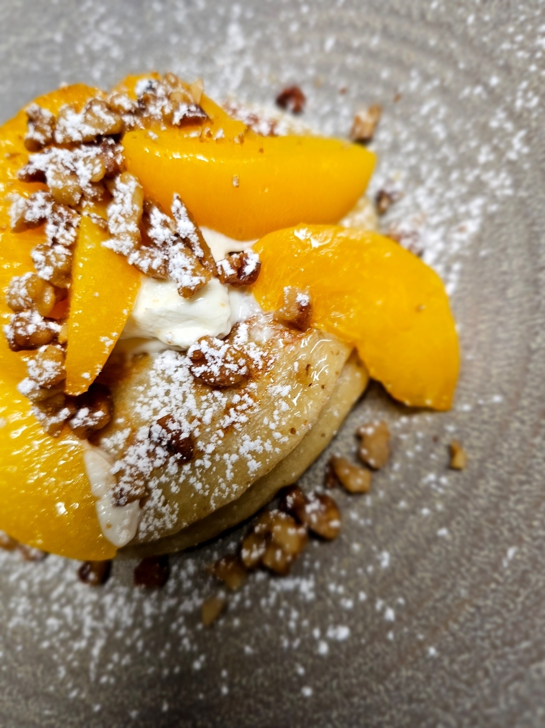Sweet pancake stack with peaches and walnuts